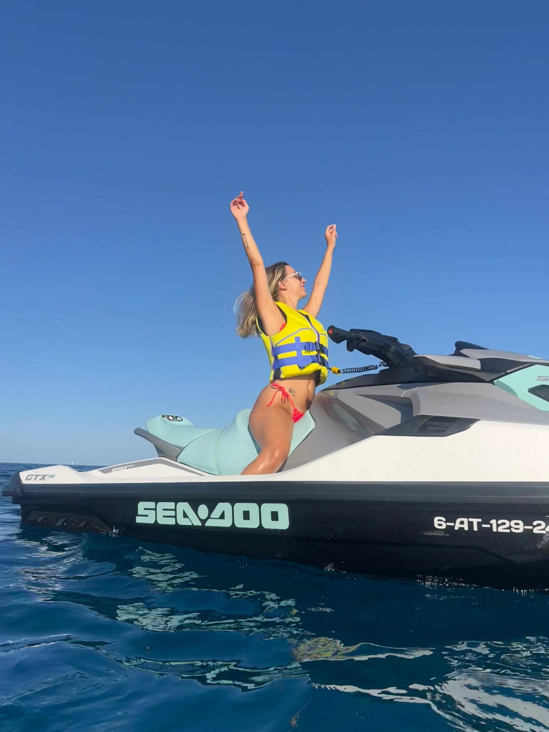 Mujer celebrando de pie sobre una moto de agua en el mar