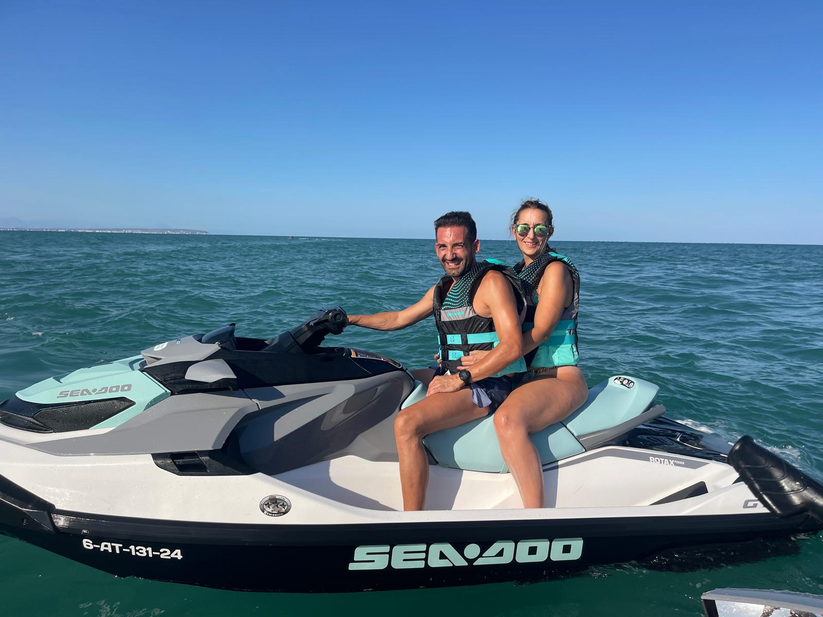 Pareja sonriente sobre una moto de agua Sea-Doo en Guardamar